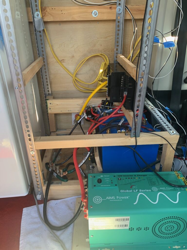 inverter/converter for van conversion with wiring and batteries in the background